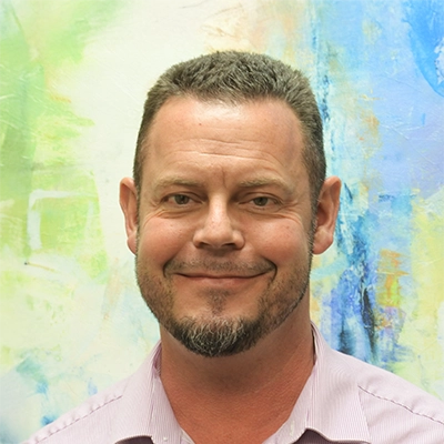 Exercise Therapist Dan Ward Smiling In Front Of Watercolor Wall